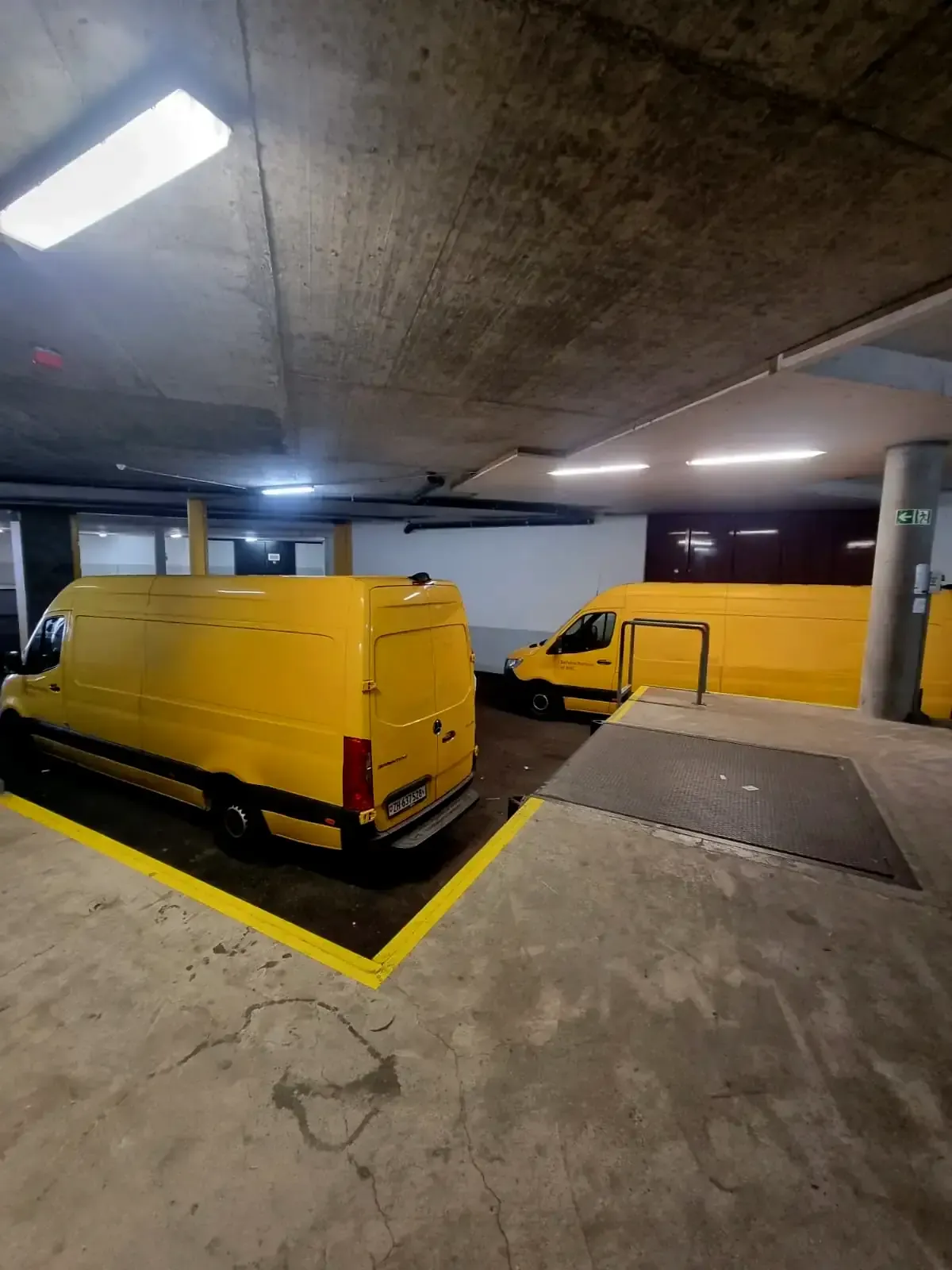 Two yellow vans parked inside a garage